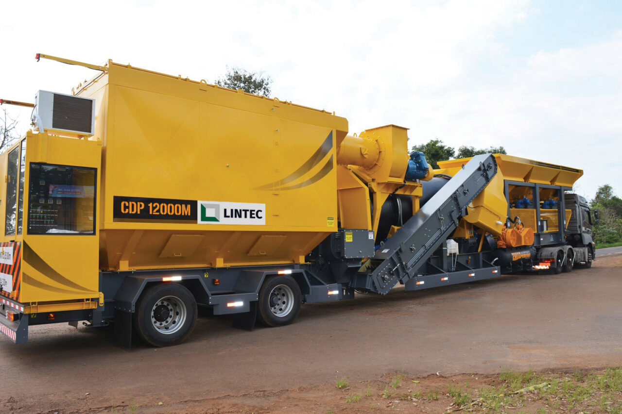 yellow Lintec CDP 6000M mobile continuous asphalt plant on a trailer chassis, featuring a drum mixer and conveyor belt system.